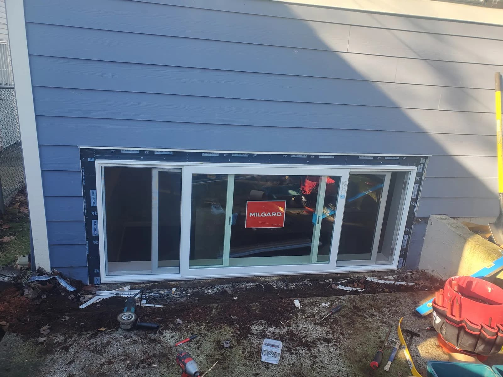 Wide lower-level residential sliding window replacement installed in grey siding