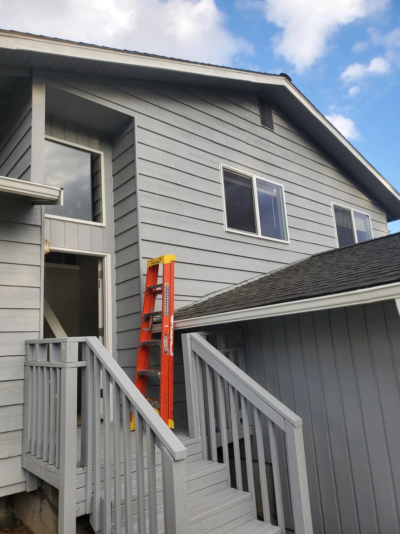 Second-story residential window replacement on a grey two-story home