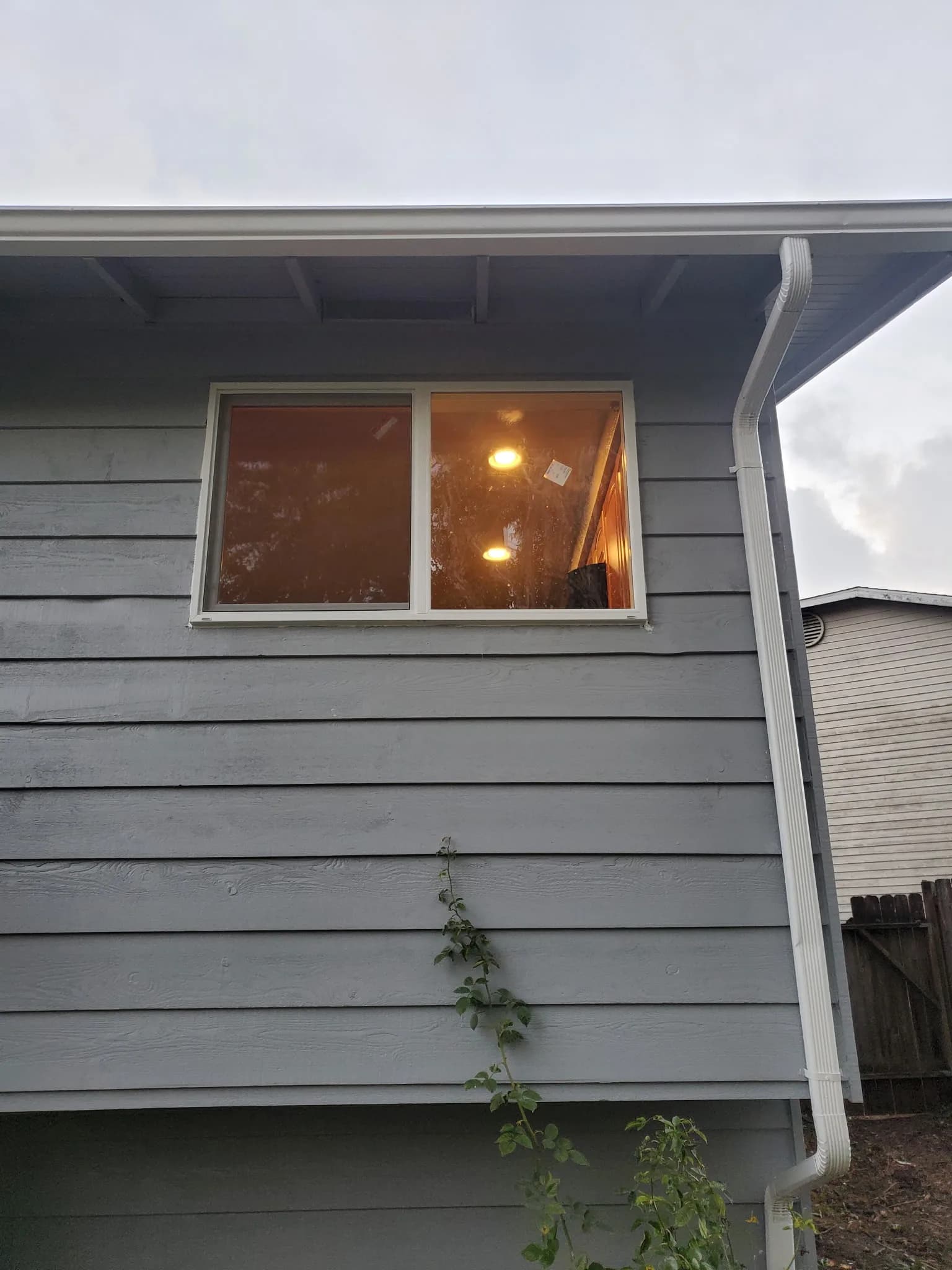 Close-up of an upper-floor residential window replacement beneath a white overhang